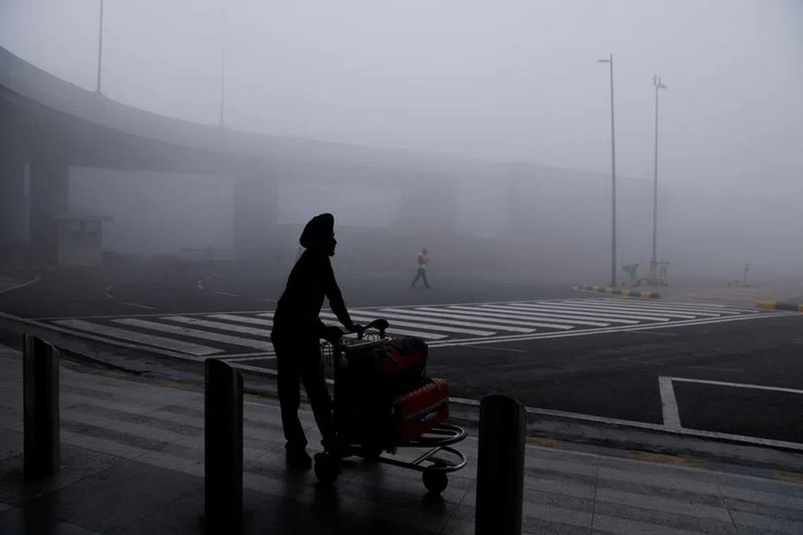 FILE PHOTO: A man is seen with his luggage cart amidst heavy fog at the Indira Gandhi International Airport in New Delhi, India, December 27, 2023. REUTERSAnushree Fadnavis/File Photo