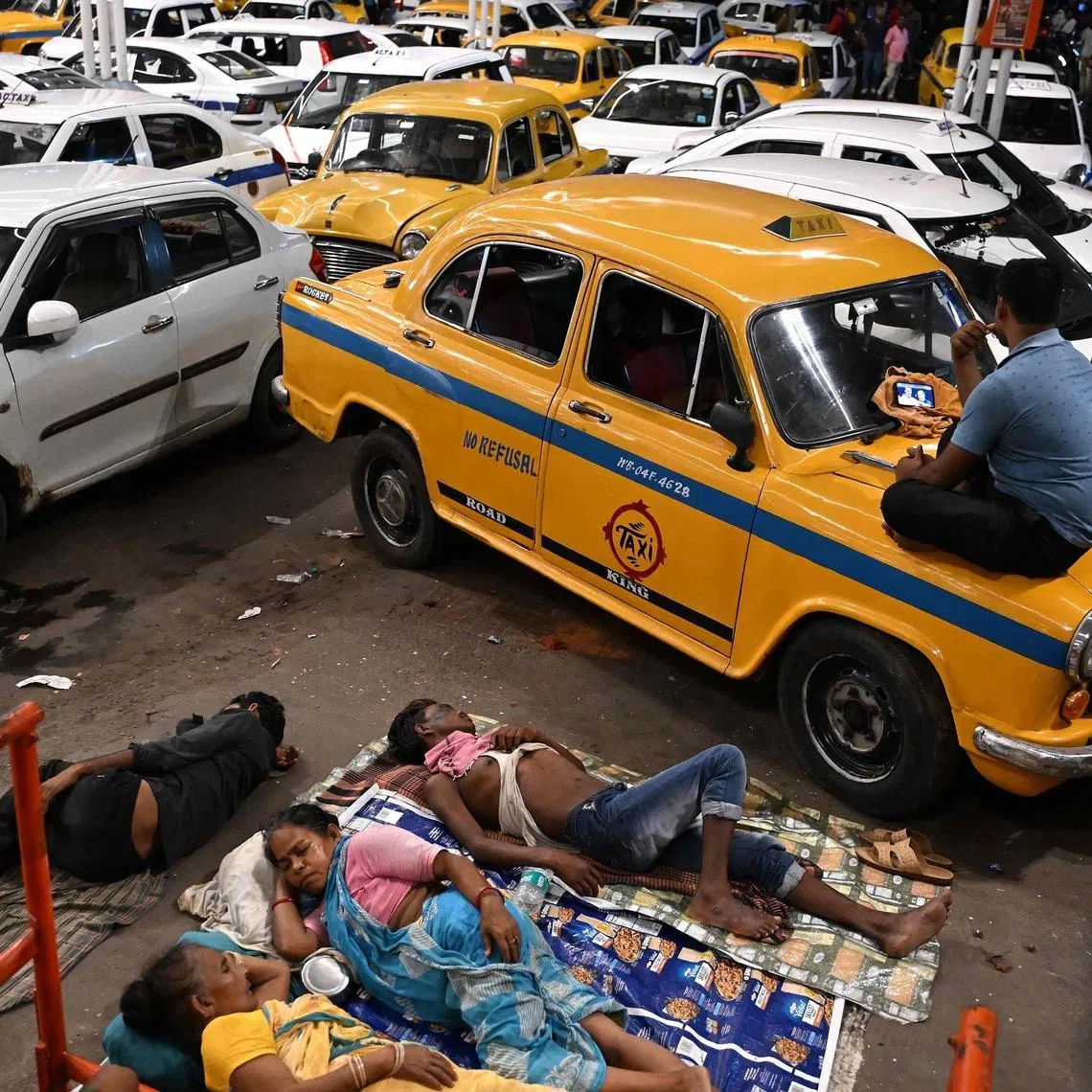 TOPSHOT - Drivers of Kolkata's iconic Hindustan Ambassador yellow taxi watch the 2026 World Cup football tournament semi-final match between England and Argentina on a mobile phone, at a taxi-stand in Kolkata on July 16, 2026. (Photo by Dibyangshu SARKAR / AFP)