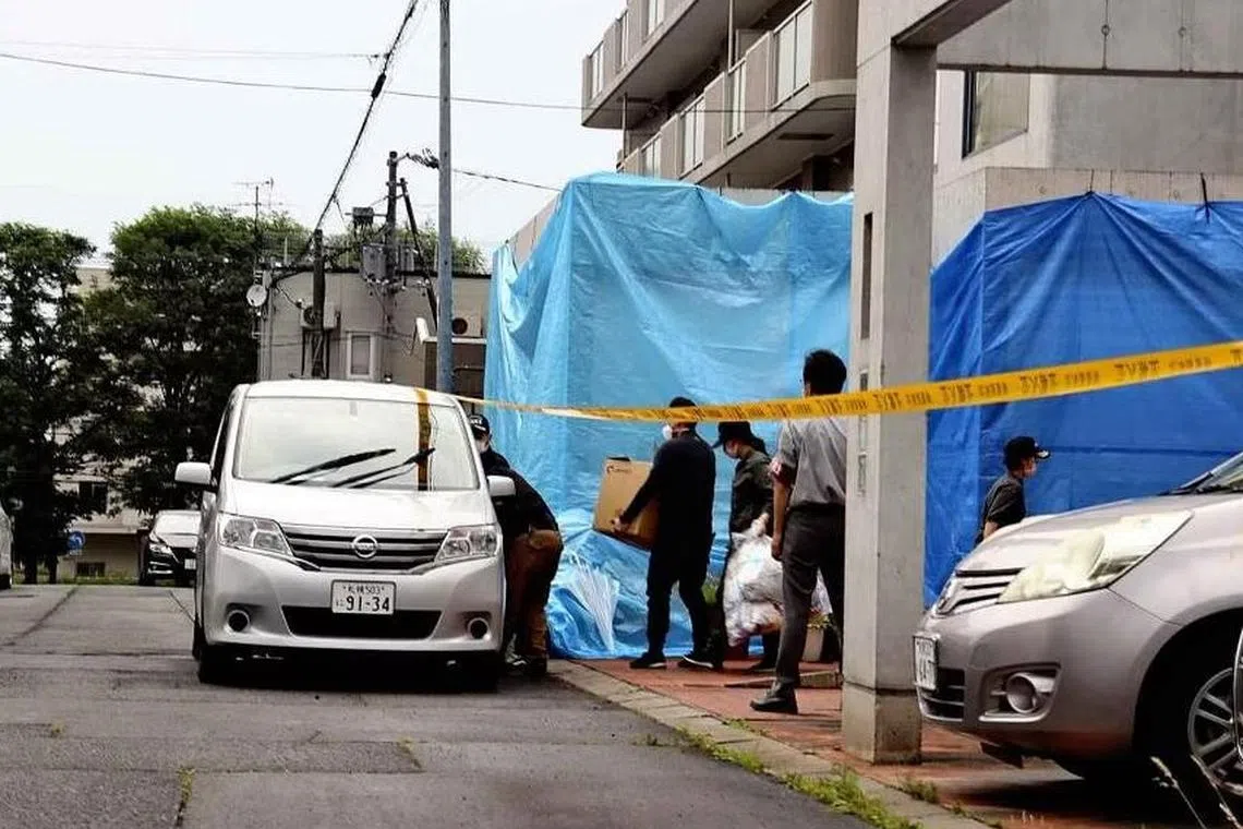 Investigators check the home of Hiroko and Osamu Tamura, who were charged, along with their daughter, for the murder of a Mr Hitoshi Ura.