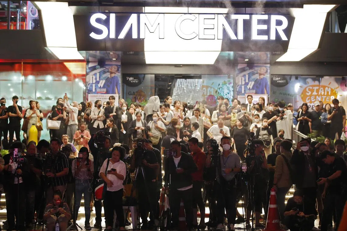 Members of the media and evacuated shoppers looking from a building opposite to the Siam Paragon Mall following gunshots in Bangkok, Thailand on October 3, 2023. 