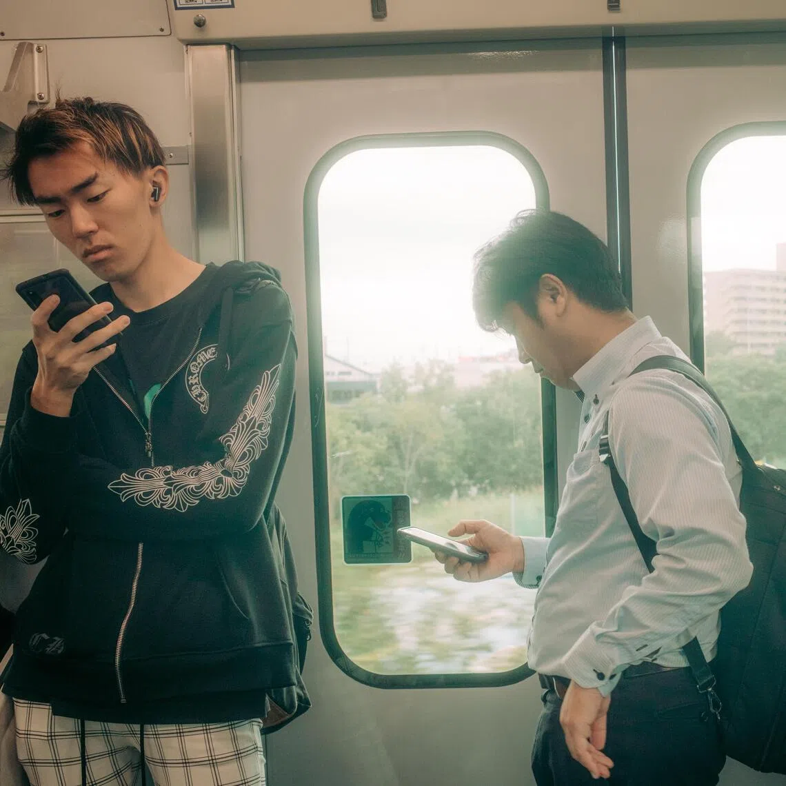 Smartphones help passengers pass the time on a train near Toyoake, Japan, on Sept. 29, 2025. Authorities in Toyoake introduced a rule limiting the use of digital devices to two hours per day outside of work and school. (Kentaro Takahashi/The New York Times)