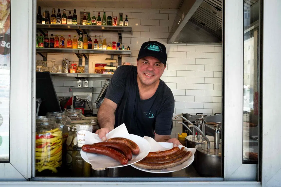 Patrick Bernhardt, employee at Vienna's oldest operating sausage stand 'Wuerstelstand LEO', poses for a photo with plates of sausages in Vienna, Austria on June 18.