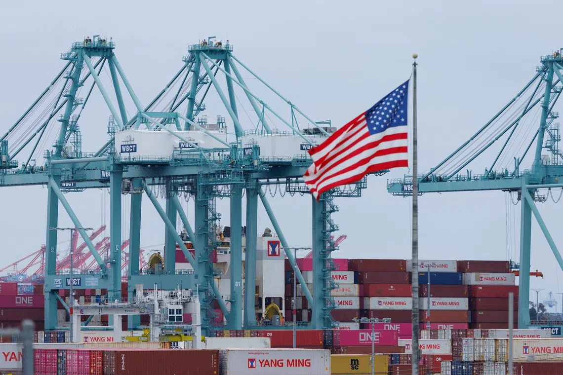 A US flag flutters near shipping containers as a ship is unloaded at the Port of Los Angeles, in San Pedro, California, on May 1, 2025.