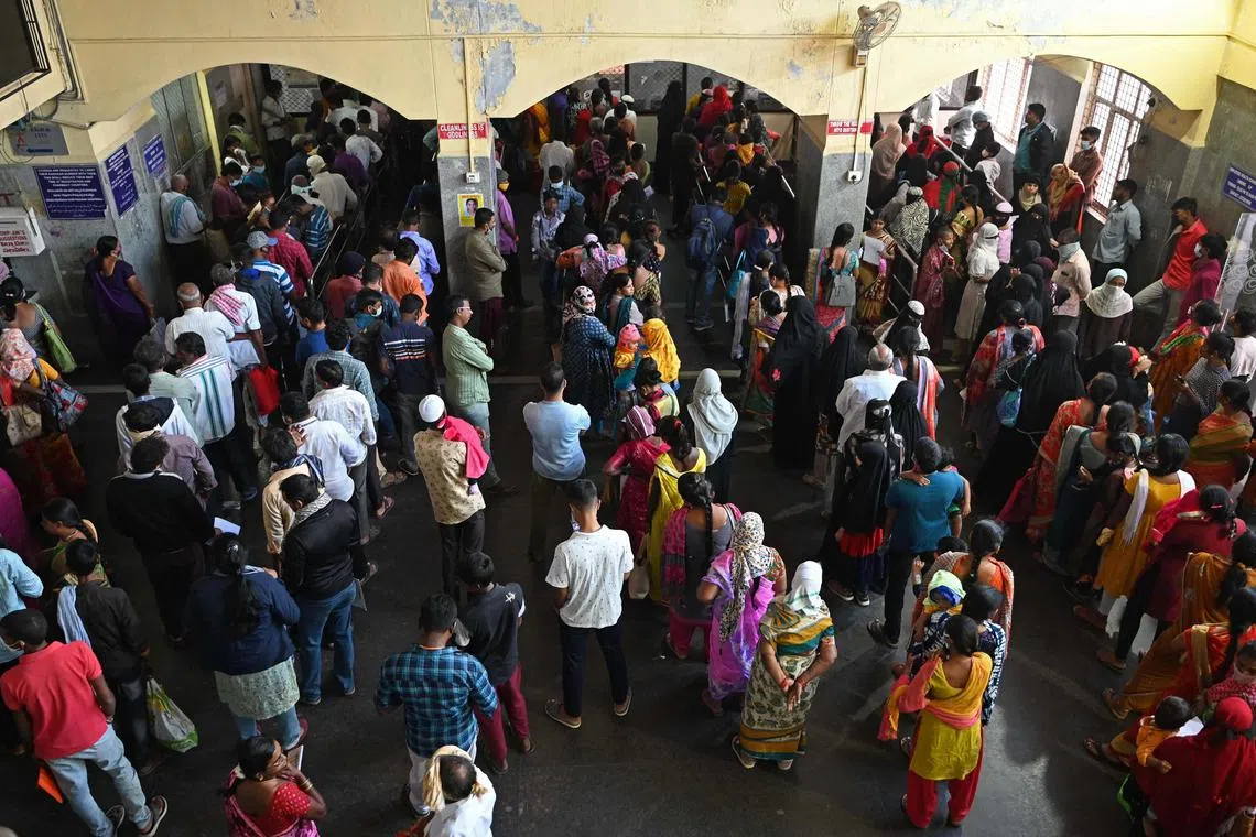 People stand in queues as they wait to get themselves registered to consult doctors for various health issues at an Out Patient Wing of a government hospital in Hyderabad on January 30, 2023. (Photo by Noah SEELAM / AFP)