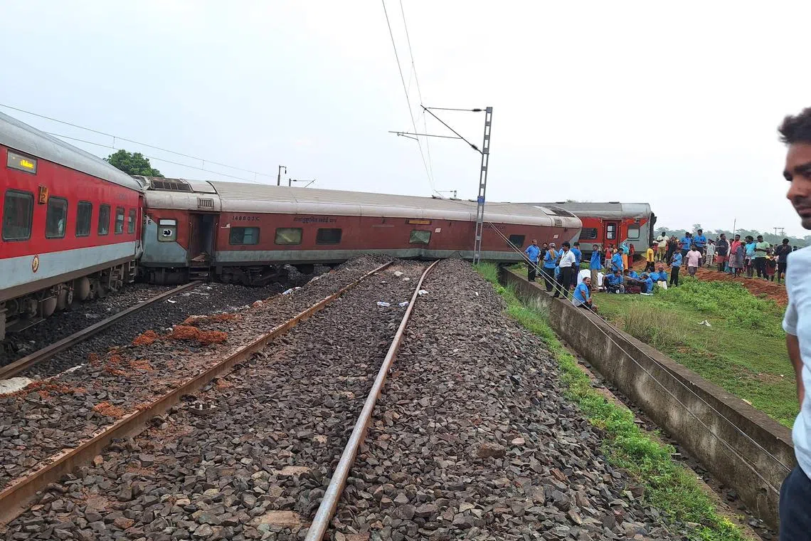 People gather near the Howrah-Mumbai Express train that derailed near Jamshedpur in India's eastern state of Jharkhand on July 30, 2024. An Indian passenger train derailed and several of its cars overturned on July 30, killing at least two people and injuring 20 others, local media reported. (Photo by Somnath SEN / AFP)