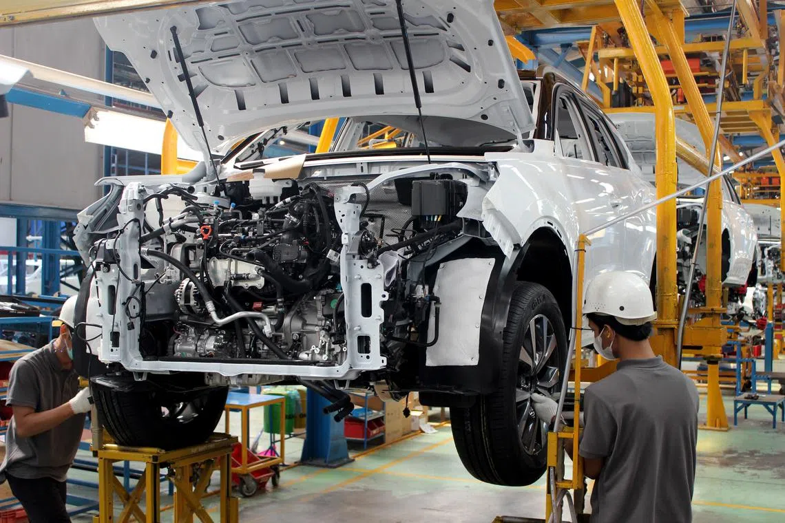 Two workers inspecting the wheels of a Chinese car at a plant run by Indonesian general assembler Handal Indonesia Motor. 