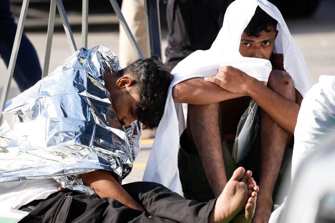 Migrants sit on the ground after a group of some 60 migrants was brought to Malta after their boat capsized close to the Mediterranean island, in Bugibba, Malta, December 12, 2025. REUTERS/Darrin Zammit Lupi