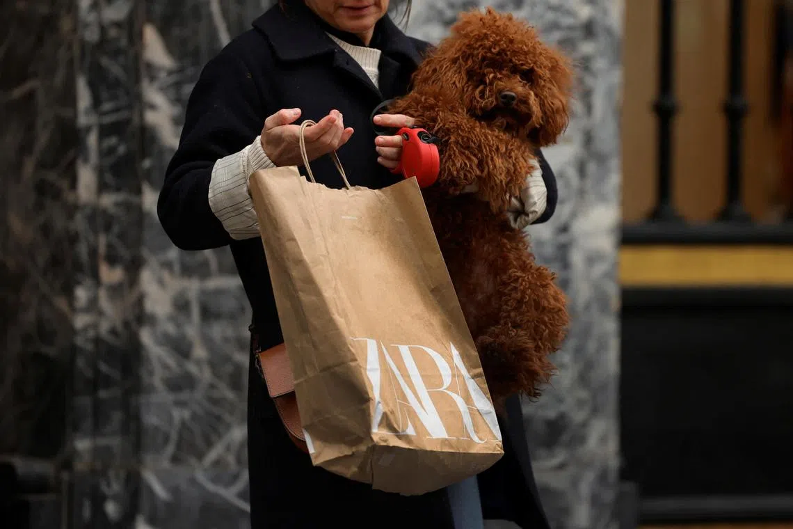 A woman carries a bag from Spanish multinational retail clothing chain Zara, while holding her dog, in the Gran Via of Bilbao, Spain, December 11, 2023. REUTERS/Vincent West