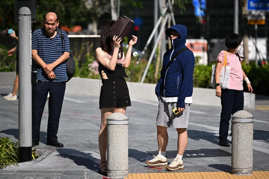 ST20230621-202390939594-Lim Yaohui-pixgeneric/
People shielding from the hot sun using handbag and sun protection long-sleeve clothing with face shield while waiting to cross Anson Road near OUE Downtown Gallery on June 21, 2023.
For stories on hot weather, climate change, rising temperatures, population, budget and environment.
(ST PHOTO: LIM YAOHUI)