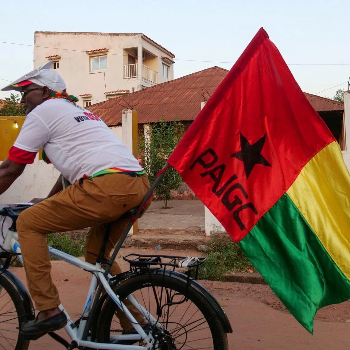 A supporter of presidential candidate Domingos Simoes Pereira rides a bicycle decorated with PAIGC flag, ahead of Sunday's presidential election in Bissau, Guinea-Bissau November 22, 2019. Picture taken November 22, 2019.  REUTERS/Christophe Van Der Perre