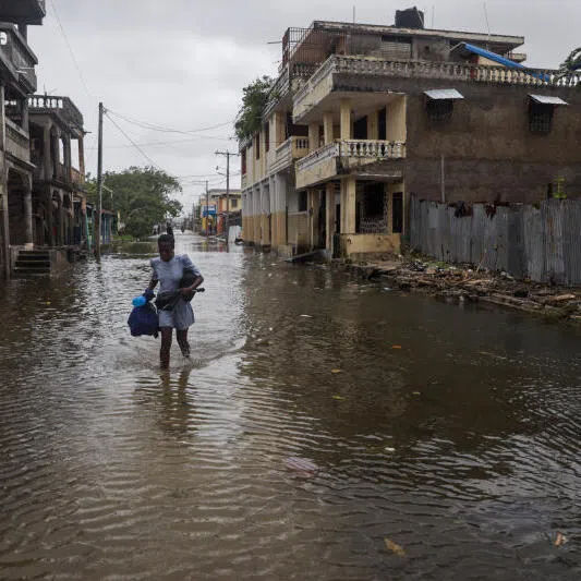 A woman holds her belongings after heavy rains from the outer bands of Hurricane Melissa flooded parts of Les Cayes, Haiti, on Oct 29.