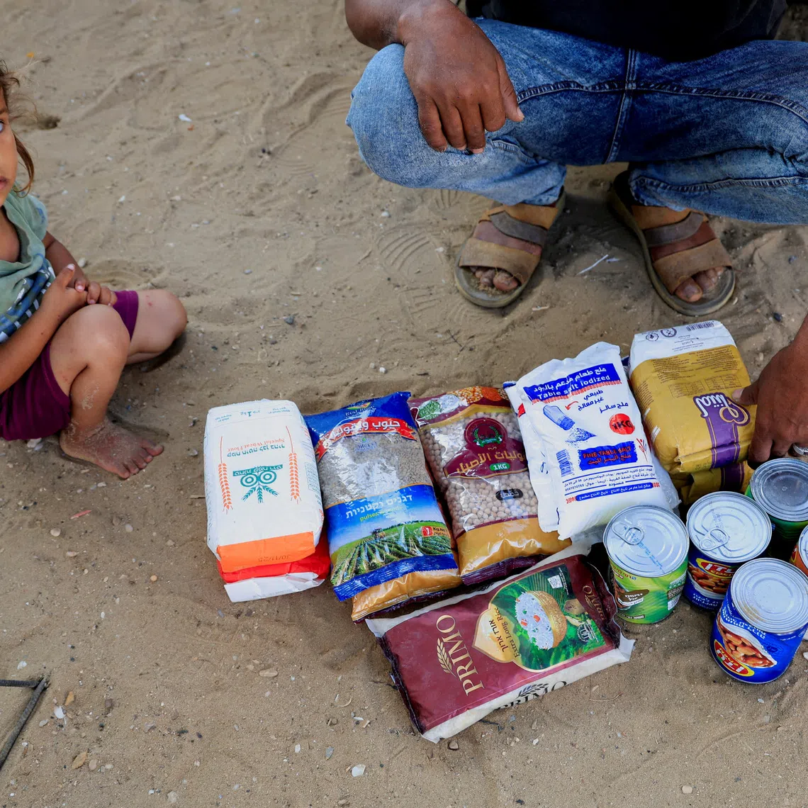 A Palestinian man, next to a child, displays the aid supplies he received from the U.S.-supported Gaza Relief Organization, in Khan Younis, southern Gaza Strip, June 5, 2025. REUTERS/Hatem Khaled/File Photo