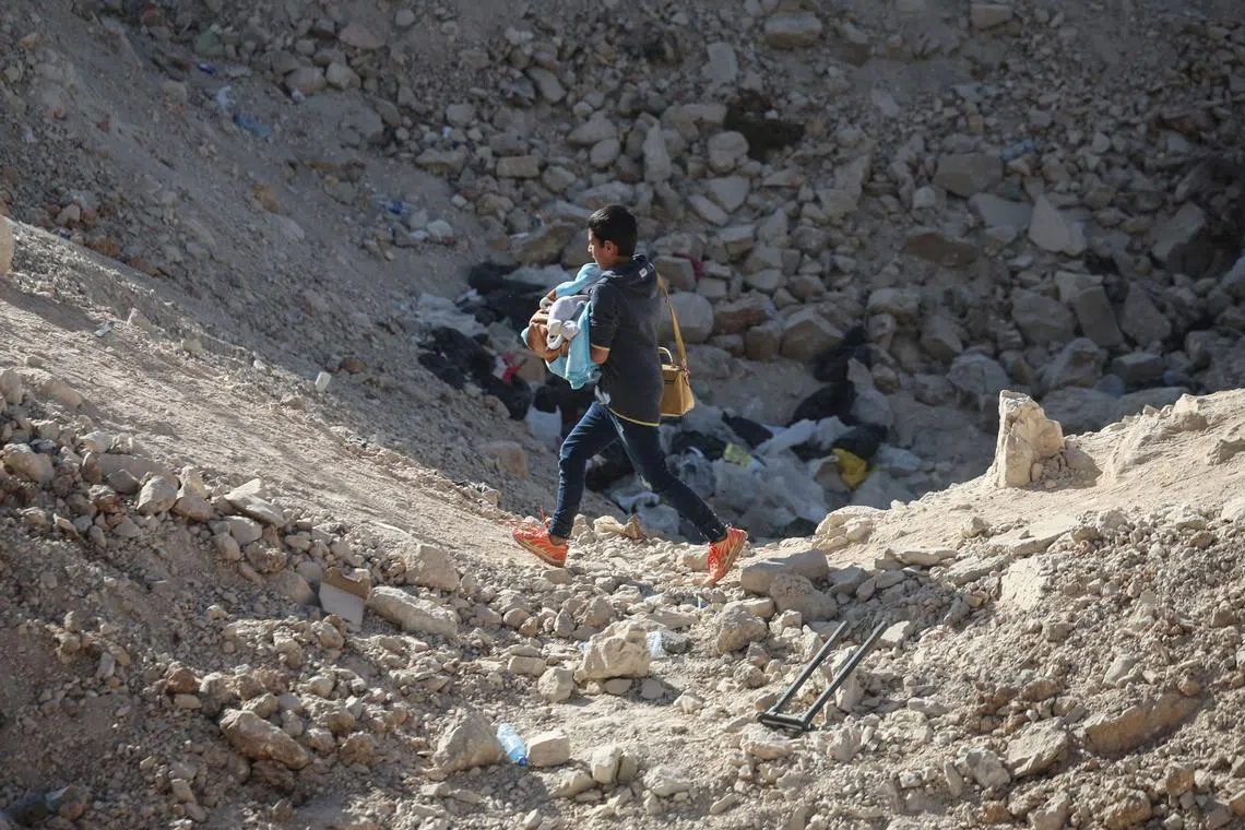 FILE PHOTO: A boy carries and infant, while crossing from Lebanon into Syria on foot, at the Masnaa border crossing, after Israeli strikes earlier this month that Lebanon's transport minister said had closed off the road to vehicles, October 14, 2024. REUTERS/Louisa Gouliamaki/File Photo