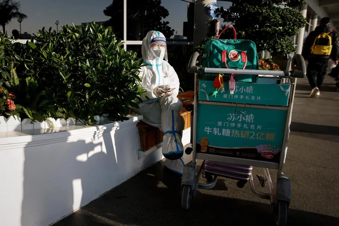 epa10378451 A woman wears a protective suit at the Xiamen Gaoqi International Airport in Xiamen, Fujian province, China, 26 December 2022. People from China's two biggest cities; Beijing and Shanghai have returned to work as the country's medical workers continue to battle a surge in Covid-19 with millions of new cases.  EPA-EFE/MARK R. CRISTINO