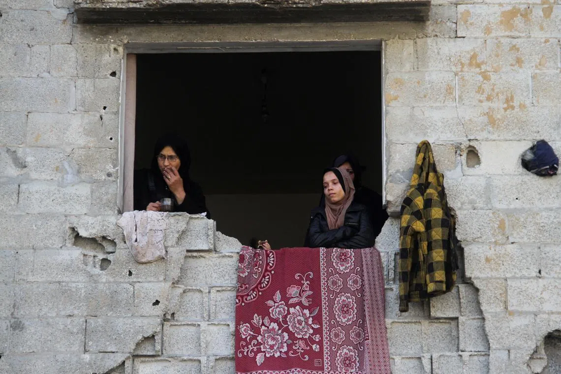 FILE PHOTO: Palestinian women stand in a window of a damaged building, amid ceasefire negotiations with Israel, in Gaza City, January 15, 2025. REUTERS/Mahmoud Issa/File Photo