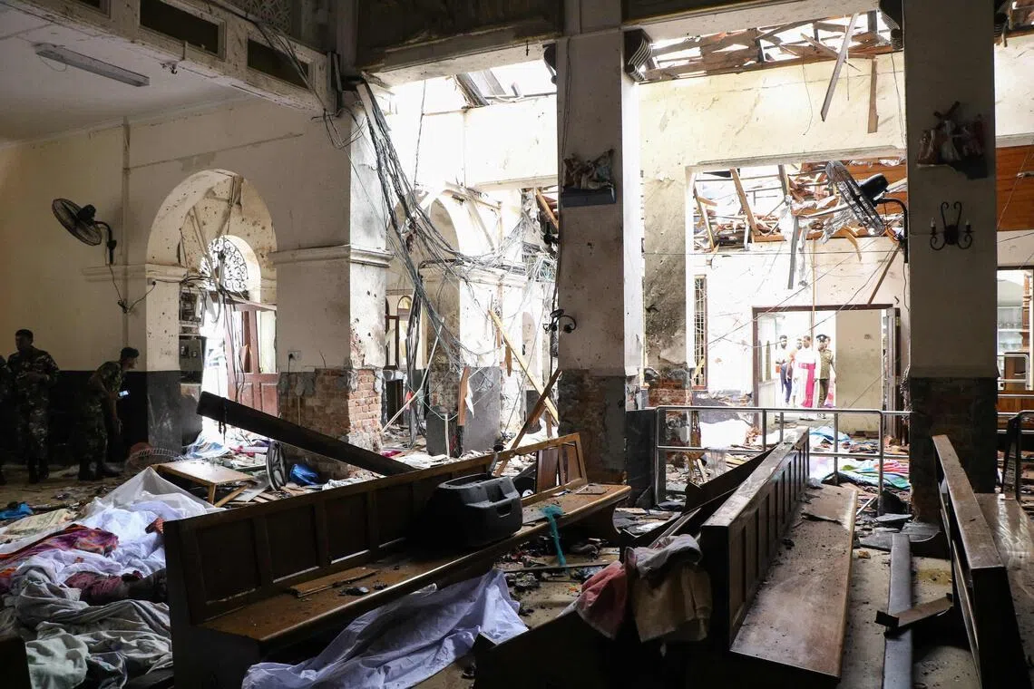 Sri Lankan security personnel walk past dead bodies covered with blankets amid blast debris at St Anthony's Shrine following an explosion in the church in Kochchikade in Colombo on April 21, 2019.