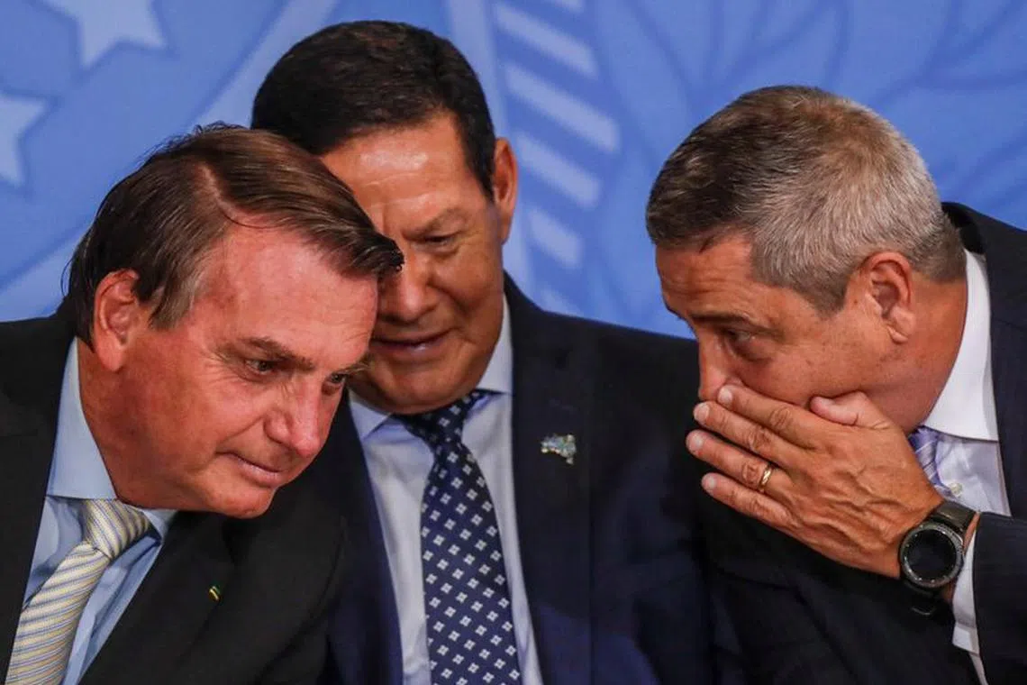 Brazil's President Jair Bolsonaro listens his chief of staff, Army General Walter Souza Braga Netto (R) near Brazil's Vice President Hamilton Mourao (C), during a ceremony at the Planalto Palace in Brasilia, Brazil February 24, 2021. REUTERS/Ueslei Marcelino