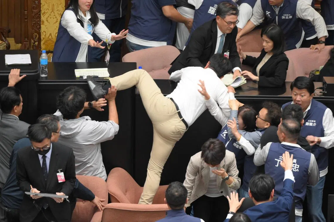 Taiwan's ruling Democratic Progressive Party (DPP) lawmaker Kuo Kuo Wen (centre) trying to jump onto the desk, during the voting for the Parliament reform bill at Parliament, in Taipei, on May 17, 2024. 
