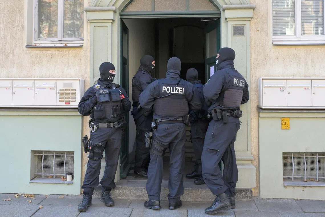 FILE PHOTO: Masked German police officers guard a house after having arrested eight suspected members of a right-wing militant group driven by racist ideology and conspiracy theories who had been training in warfare for the downfall of the modern German state, in Dresden, Germany, November 5, 2024.   REUTERS/Matthias Rietschel/File Photo