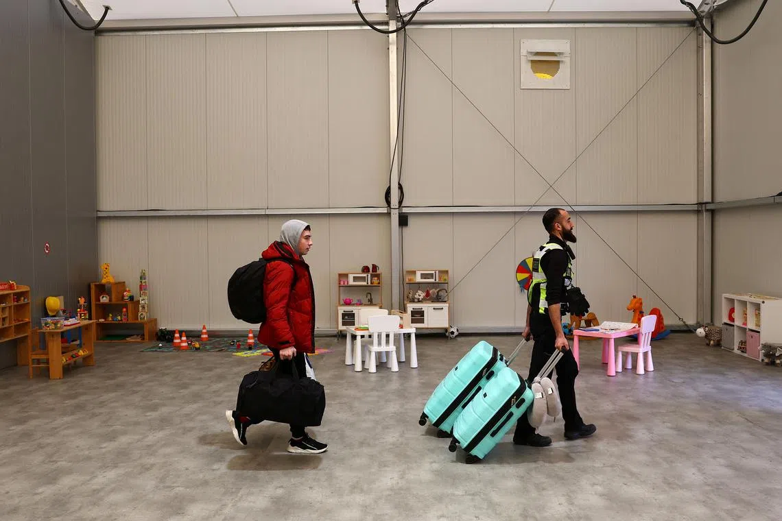 FILE PHOTO: A security member helps to move the belongings of a family fleeing the Russian attack on Ukraine after their arrival at a temporary refugee shelter in Hanau, Germany, March 2, 2023.  REUTERS/Kai Pfaffenbach