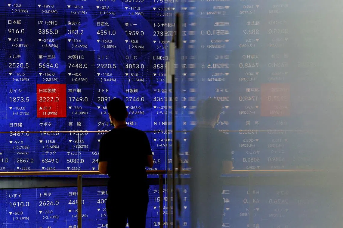 FILE PHOTO: A man stands next to an electronic stock quotation board inside a building in Tokyo, Japan August 2, 2024. REUTERS/Issei Kato/File Photo