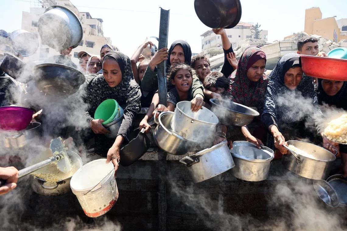 Palestinian women and girls elbow pleading for cooked rice from a charity kitchen in Gaza City on Aug 23.