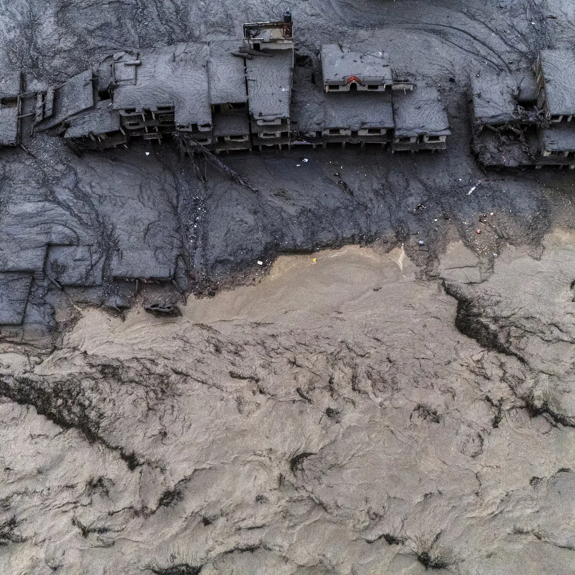 A drone view shows damaged buildings covered in mud next to the Likhu River following deadly flash floods and mudslides in Devighat, Nuwakot district, Nepal, on Aug 30.