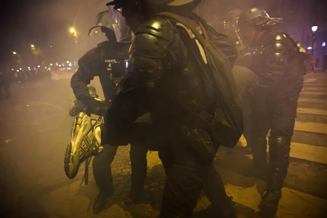 Police arrest a man as clashes erupt following celebrations by PSG fans on the Champs-Elysees.