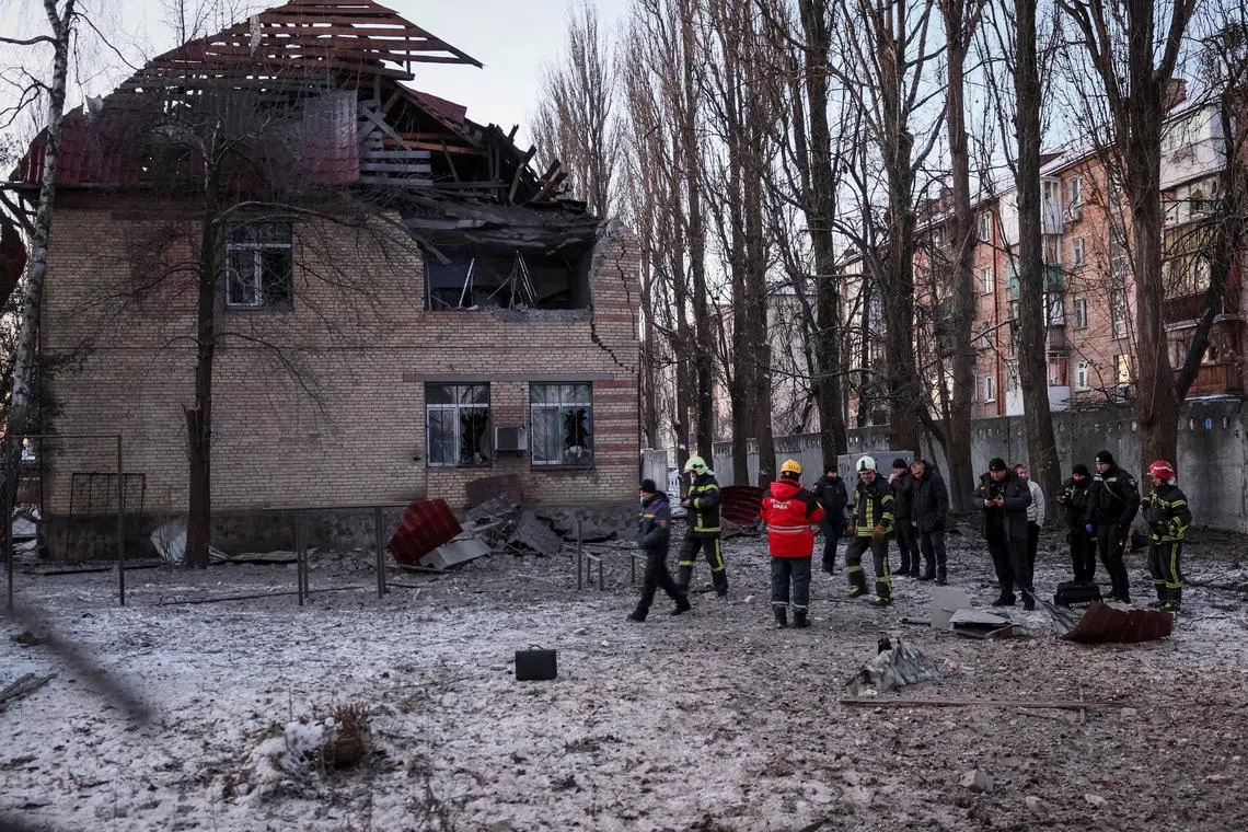 Rescuers and police officers examine parts of the drone at the site of a destroyed building.