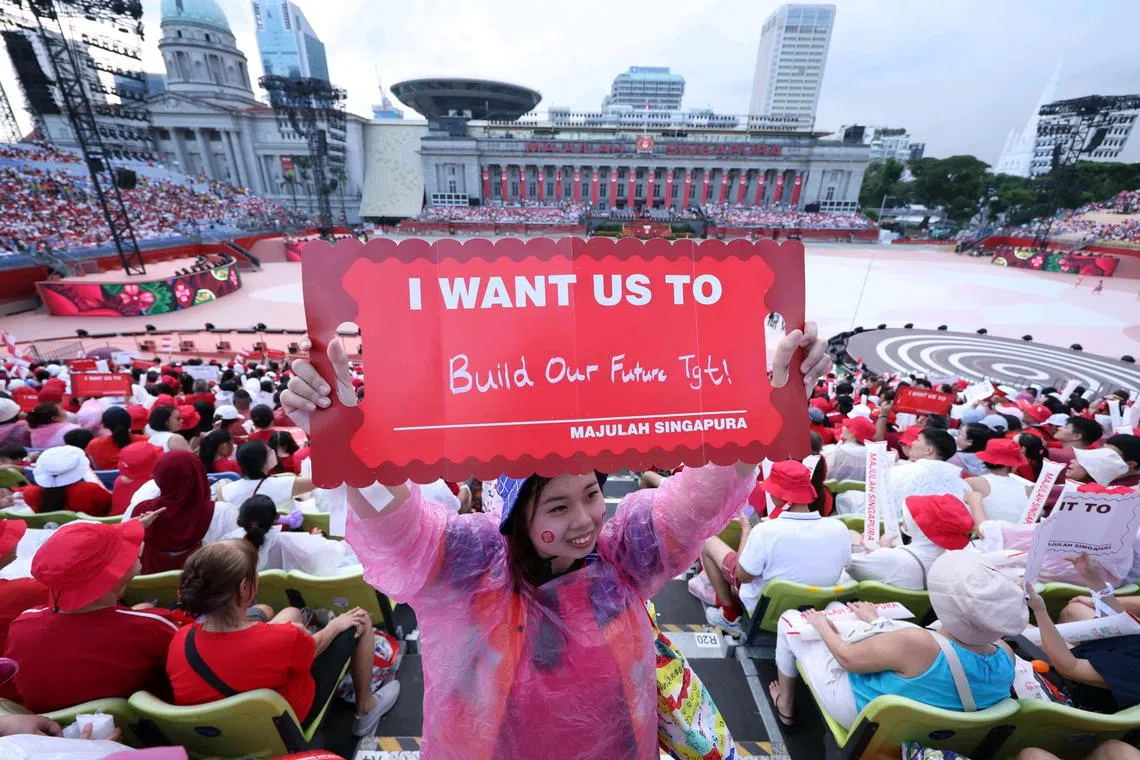 Volunteers holding up placards bearing their personal wishes during the National Day Parade at the Padang on Aug 9, 2025. 