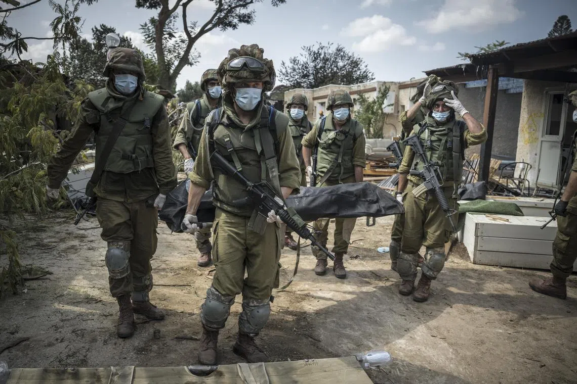 Israeli soldiers carry a body in Kfar Azza, an Israeli village just across the border from Gaza that was attacked by Palestinian gunmen.