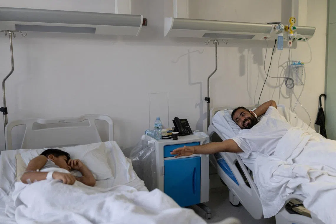 Syrian refugee Abdulaziz Aldarwish, 32, reaches out his hand towards his son Yahia Aldarwish, 10, from his hospital bed shortly before a kidney transplant in which Abdulaziz is the donor, at the Onassis National Transplant Center, in Athens, Greece, January 22, 2026. REUTERS/Stelios Misinas