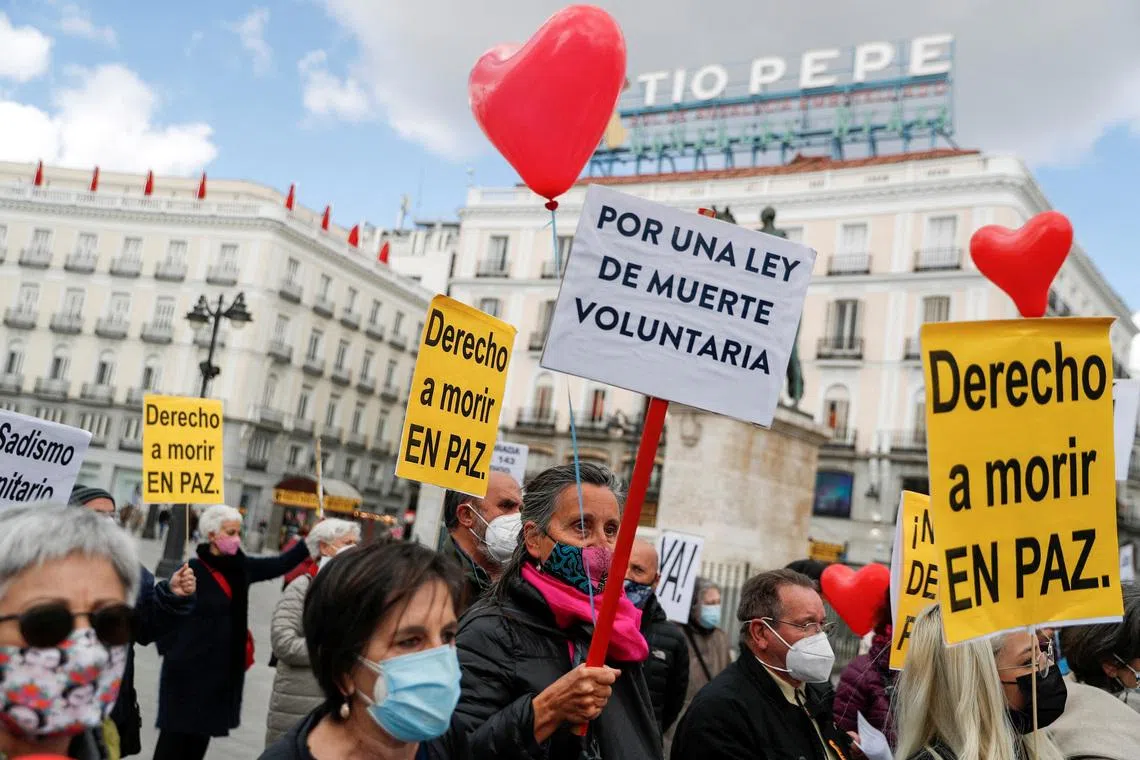 FILE PHOTO: Supporters of a law to legalise euthanasia gather as the Spanish Parliament votes to approve it in Madrid, Spain, March 18, 2021. The banners read: \"Right to die in peace\", \"For a law to die voluntarily\" REUTERS/Susana Vera/File Photo