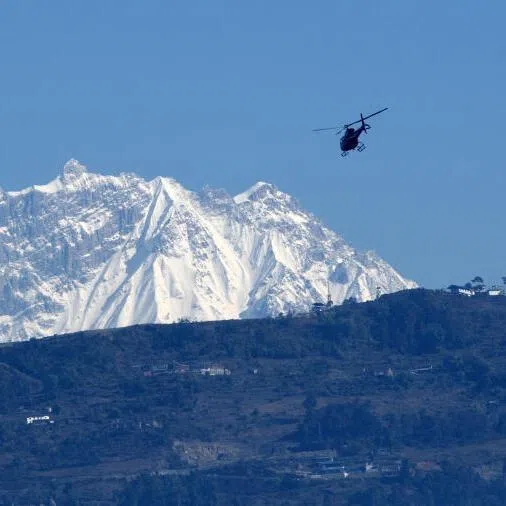 A helicopter flies with rescue team in front of the Annapurna mountain range, in Pokhara, some 200 km west of Kathmandu on January 22, 2020.