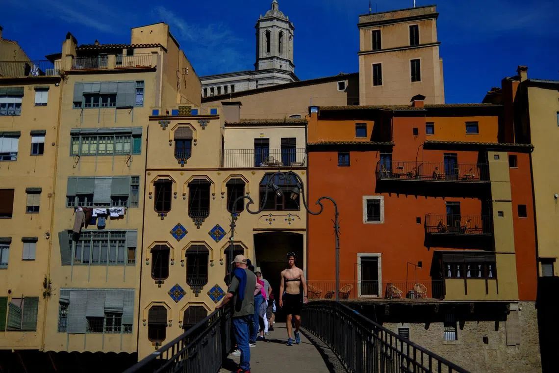 Tourists stand on a bridge in Girona, Spain, April 6, 2026. REUTERS/Nacho Doce