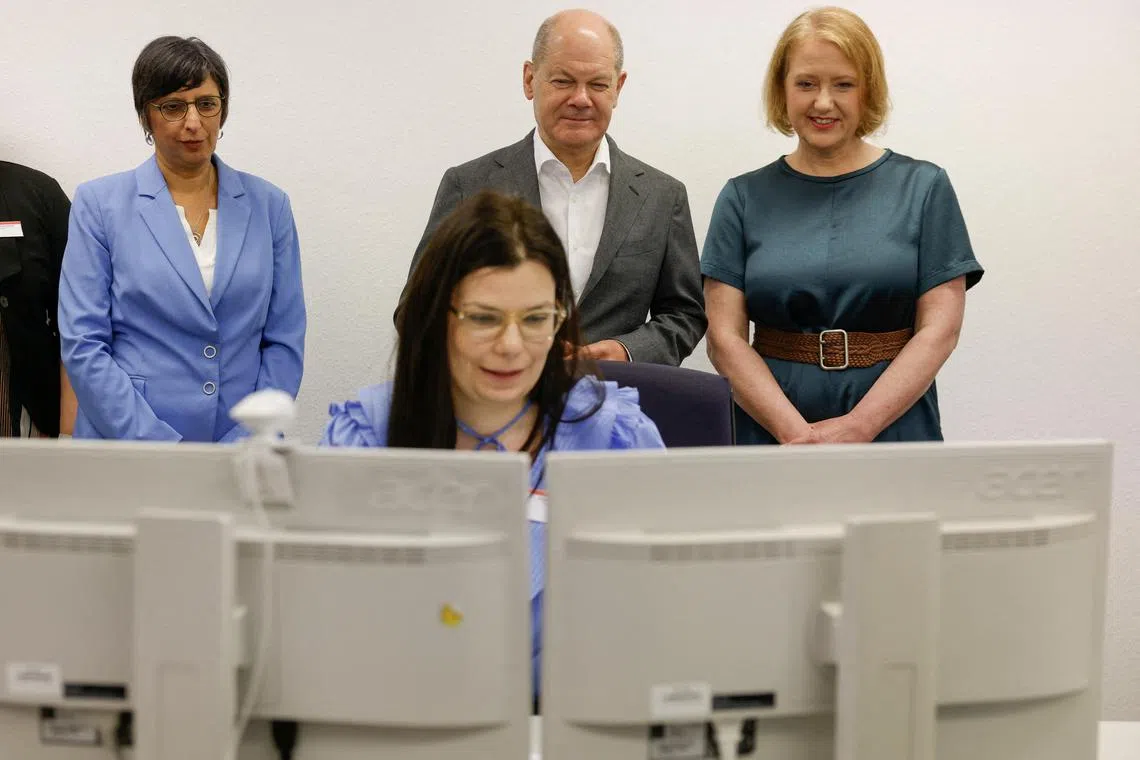 FILE PHOTO: German Chancellor Olaf Scholz, German Minister for Family Affairs, Senior Citizens, Women and Youth Lisa Paus and the chairwoman of the Family Center Vanessa Ahuja watch team leader Ioana Ullrich working on her computer during their visit at the Family benefit Center of Berlin-Brandenburg on June 19, 2023, in Potsdam. ODD ANDERSEN/Pool via REUTERS/File Photo