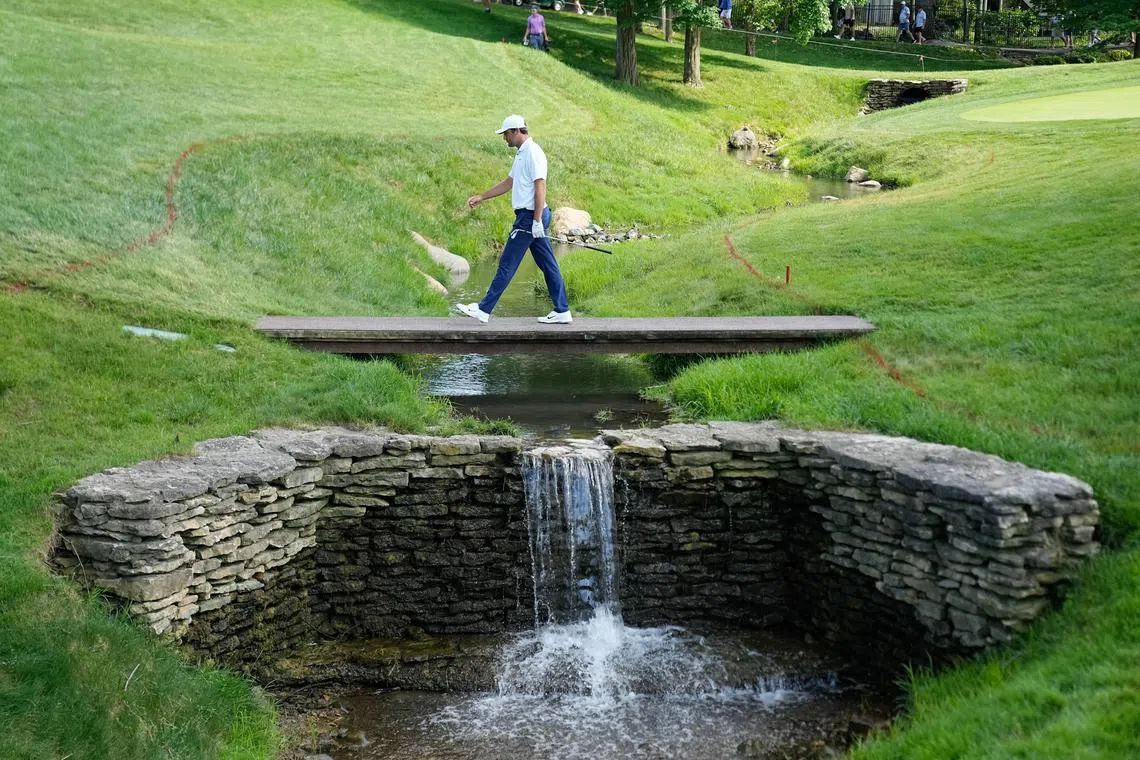 Scottie Scheffler walks across a creek on the 17th hole during the second round of the PGA Memorial Tournament at Muirfield Village Golf Club.