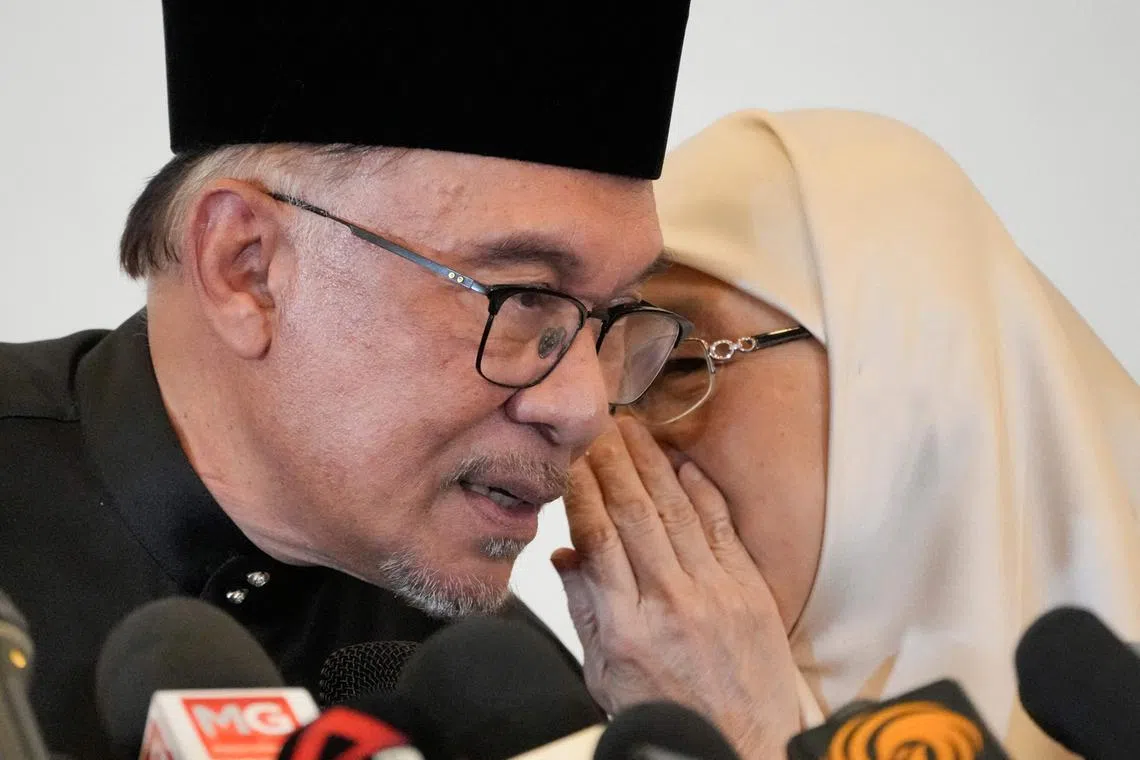 Malaysia's newly appointed prime minister Anwar Ibrahim (L) speaks with his wife Wan Azizah during a news conference in Kuala Lumpur, Malaysia on Nov 24, 2022.