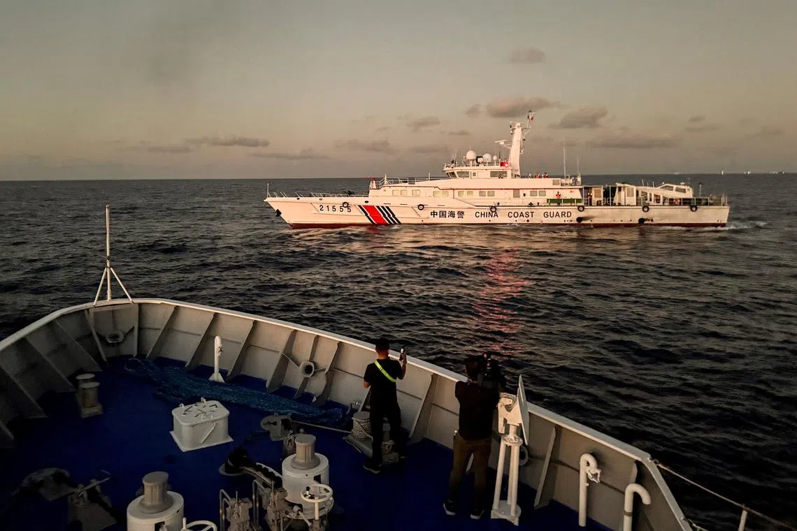 FILE PHOTO: Members of the media take footage of a Chinese Coast Guard vessel blocking a Philippine Coast Guard vessel on its way to a resupply mission at Second Thomas Shoal in the South China Sea, March 5, 2024. REUTERS/Adrian Portugal/File Photo
