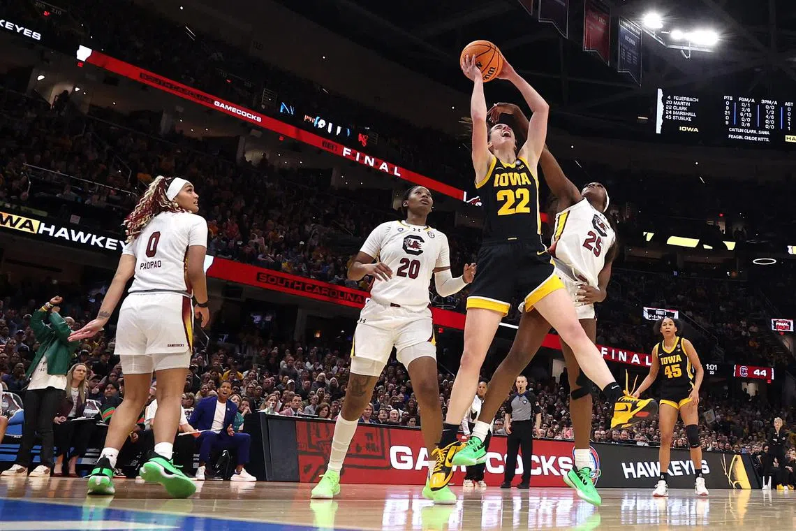 Caitlin Clark (No. 22) of the Iowa Hawkeyes working to shoot around Sania Feagin (No. 20) and Raven Johnson (No. 25) of the South Carolina Gamecocks in the 2024 NCAA Women's basketball tournament.
