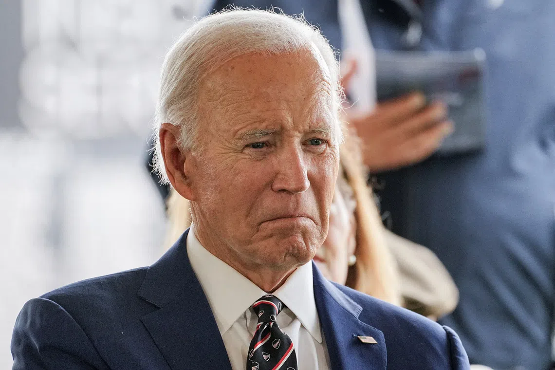 A man in a dark suit and white shirt looking serious.