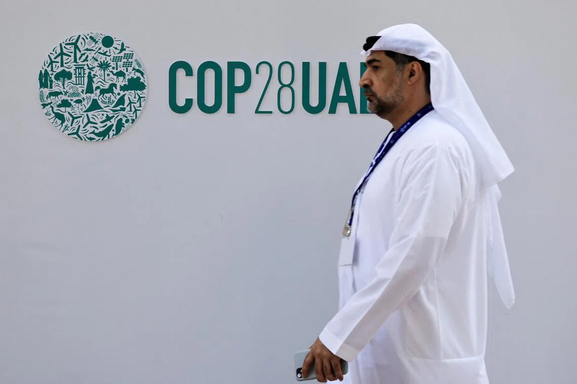 A delegate walks past a logo of the COP28 climate summit in Dubai, United Arab Emirates, December10, 2023. REUTERS/Thaier Al Sudani