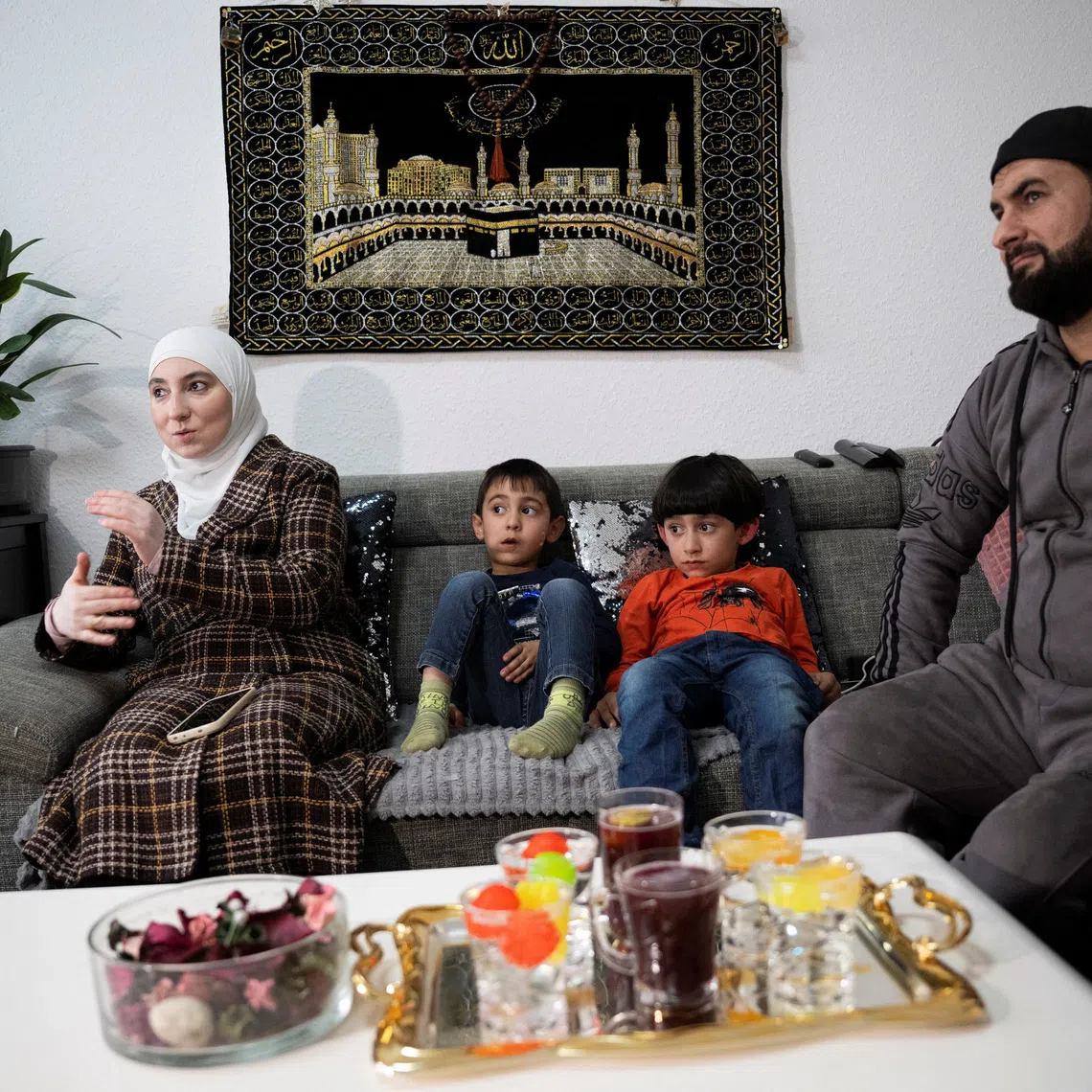Shahad Najeeb, 38, from Iraq, speaks next to her children, Zaid, 4, and Khaleed, 7, and her husband, Mahmoud Hmouech, 47, from Syria, in their apartment in Rostock on Sept 17.
