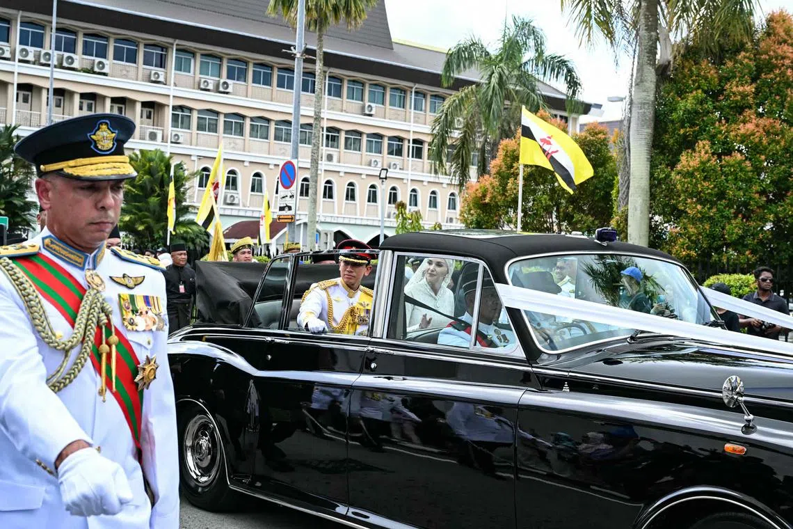 Prince Abdul Mateen and his bride Anisha Rosnah waving from their car during the wedding procession in Brunei's capital Bandar Seri Begawan on Jan 14, 2024. 