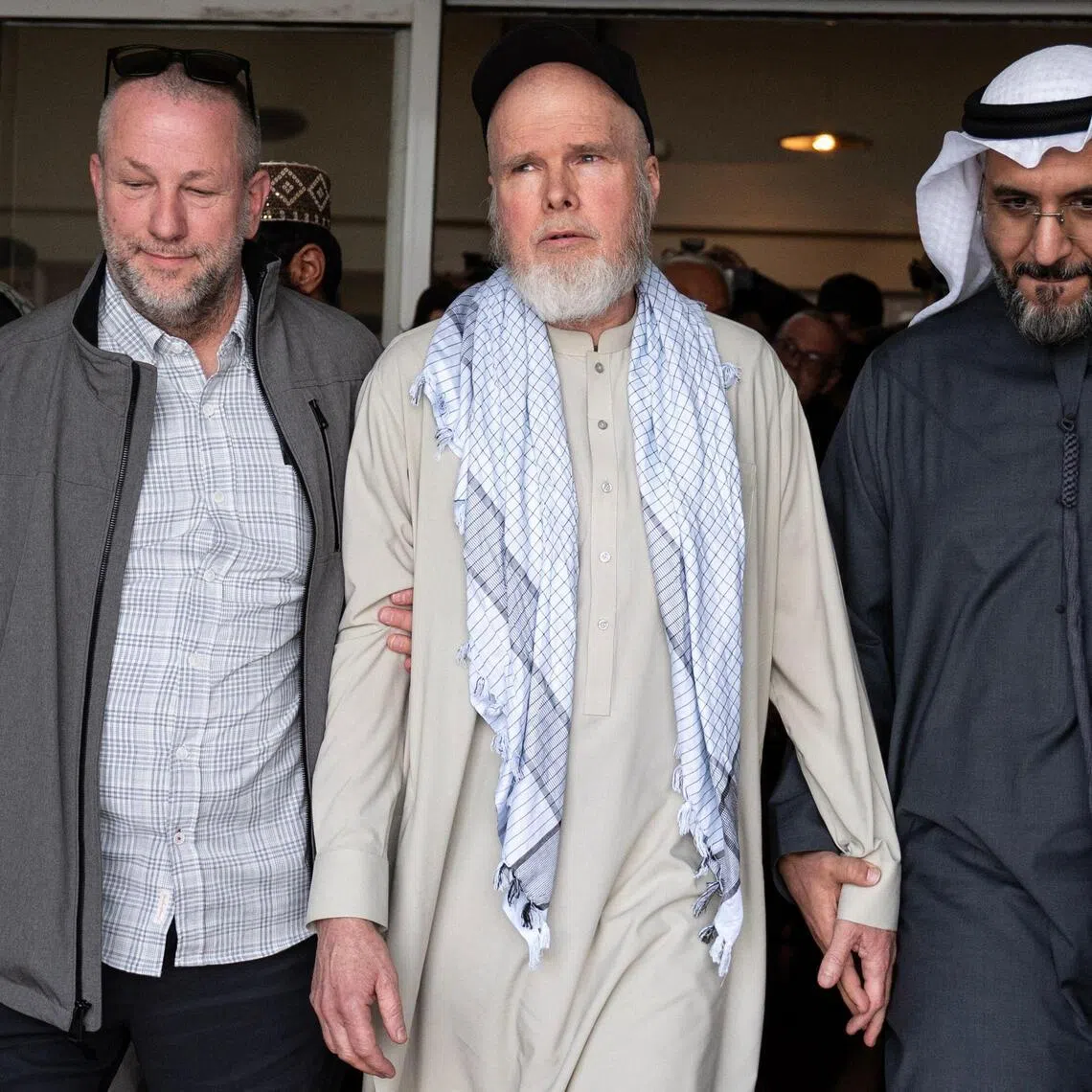 US citizen Dennis Coyle (C) upon his release by the Taliban, walks with the UAE ambassador to Kabul Saif Mohammed Al-Ketbi (R) toward a chartered aircraft at the airport in Kabul on March 24, 2026. Afghanistan's Taliban government announced on March 24 that it was freeing a US national who had been detained for more than a year. The foreign ministry said the family of linguist and researcher Dennis Coyle had written to the supreme leader of Afghanistan, requesting his release for Eid. (Photo by Wakil KOHSAR / AFP)