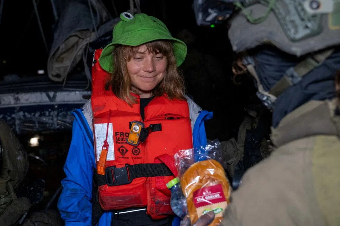An Israeli solider passes a bun to Greta Thunberg onboard the Gaza-bound British-flagged yacht \"Madleen\" after Israeli forces boarded the charity vessel as it attempted to reach the Gaza Strip in defiance of an Israeli naval blockade, in this still image released on June 9, 2025.  Israel Foreign Ministry via X/Handout via REUTERS