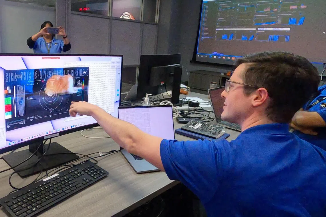 Members of the DSOC team react to the first high-definition streaming video to be sent via laser by the DSOC tranceiver aboard the Psyche spacecraft, nearly 19 million miles from Earth, featuring a cat named Taters, on December 11, 2023 at NASA's Jet Propulsion Laboratory in Pasadena, California. NASA on December 18, 2023 announced it had used a state-of-the-art laser communication system on a spaceship 19 million miles (31 million kilometers) away from Earth -- to send a high-definition cat video. The 15-second meow-vie featuring an orange tabby named Taters is the first to be streamed from deep space, and demonstrates it's possible to transmit the higher-data-rate communications needed to support complex missions such as sending humans to Mars. (Photo by Handout / NASA/JPL-Caltech / AFP) / RESTRICTED TO EDITORIAL USE - MANDATORY CREDIT "AFP PHOTO / NASA / JPL-Caltech" - NO MARKETING NO ADVERTISING CAMPAIGNS - DISTRIBUTED AS A SERVICE TO CLIENTS