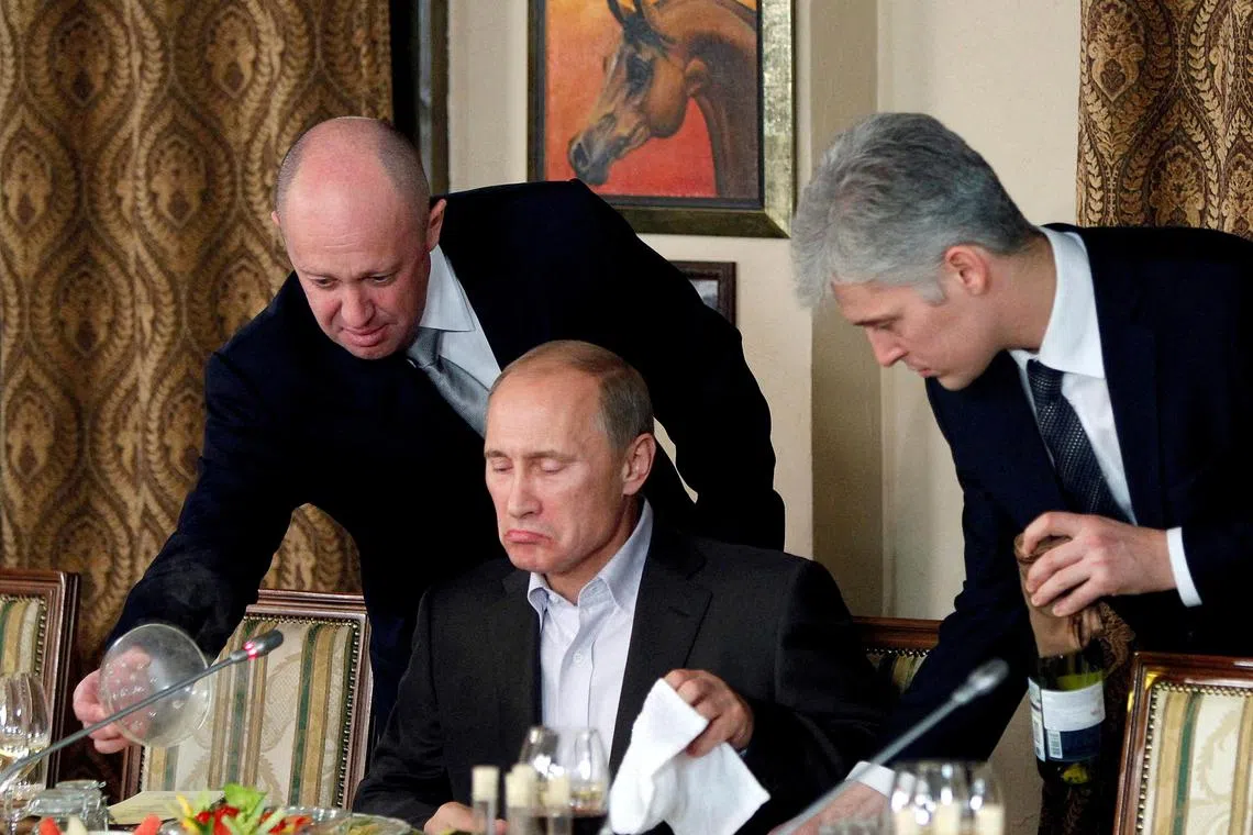 FILE PHOTO: Evgeny Prigozhin (L) assists Russian Prime Minister Vladimir Putin during a dinner with foreign scholars and journalists at the restaurant Cheval Blanc on the premises of an equestrian complex outside Moscow November 11, 2011. REUTERS/Misha Japaridze/Pool/File Photo