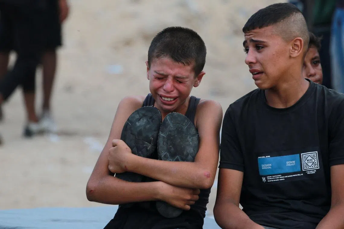 A boy hugs the shoes of his late father, who was killed on July 22 following Israeli bombardment of Khan Younis.