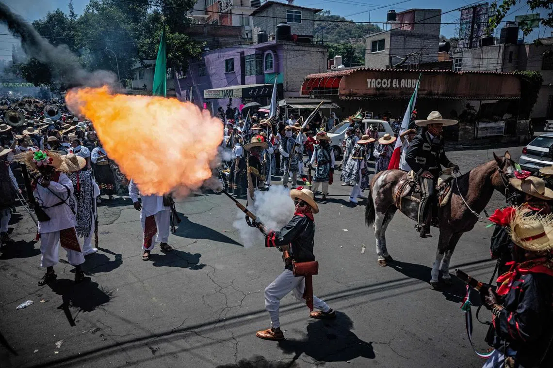 A man in costume firing a rifle on May 5 in Mexico City during a parade honouring the Battle of Puebla, which commemorates the clash between Mexican and French troops in 1862. 